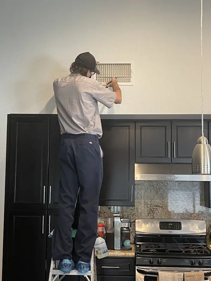 Technician inspecting an air vent during HVAC service in Sidney
